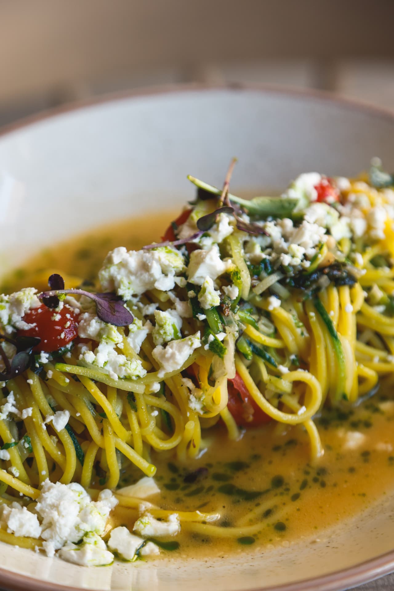 Pasta in broth with crumbled cheese and cherry tomatoes at Nōesis